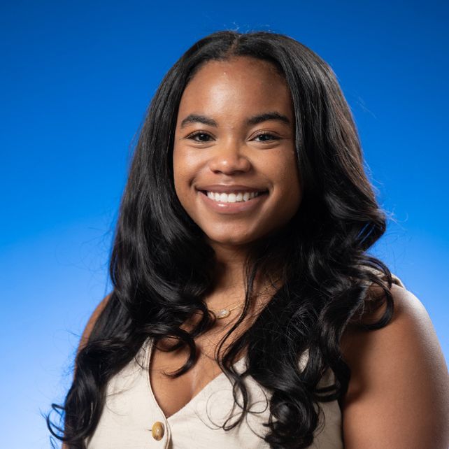 Loren Gonzalez smiling in a professional headshot against a bright blue background