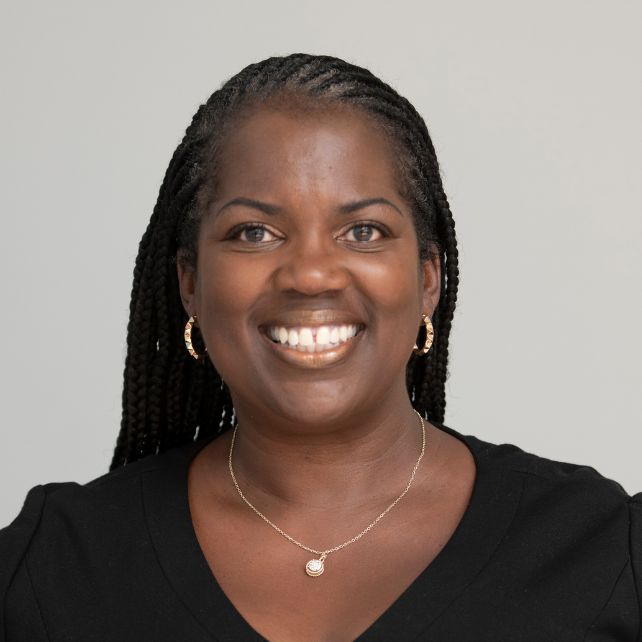Alisa Toney smiling in a professional headshot wearing a black top and gold pendant necklace against a light gray background
