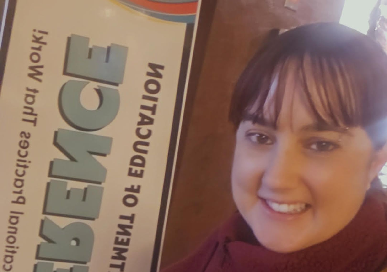Woman smiling in a selfie next to a science education conference banner