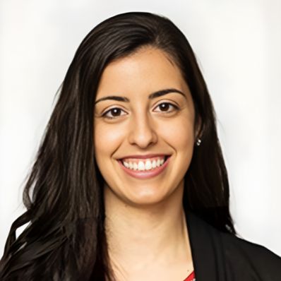 Elisa Giusto smiling in a professional headshot wearing a red top and black blazer against a light gray background