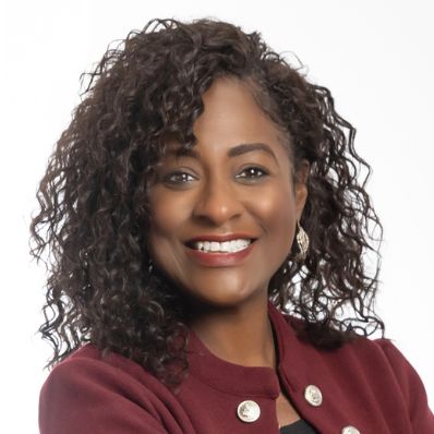 Shanda Lucas O'Dennis smiling in a professional headshot wearing a burgundy blazer against a light gray background