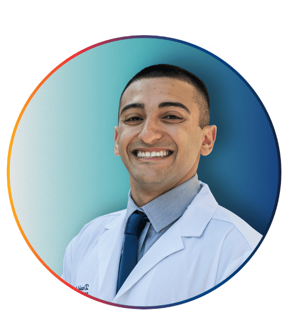 PCOM student in a white coat, gray shirt, and navy tie smiling in a circular graphic frame with red and blue accents
