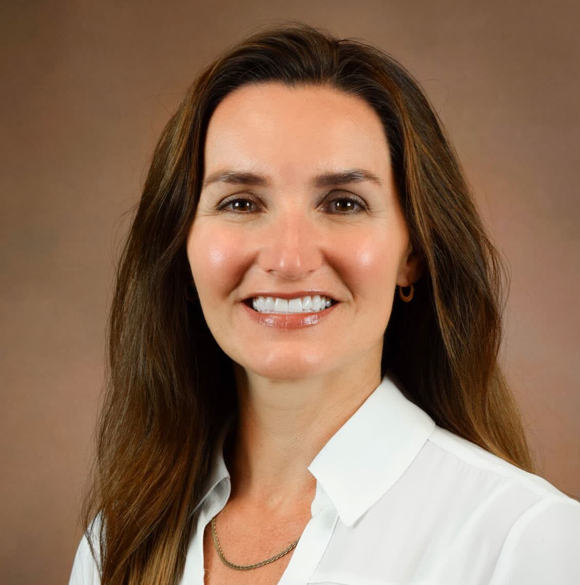 Jennifer Shaw smiling in a white blouse against a light brown background